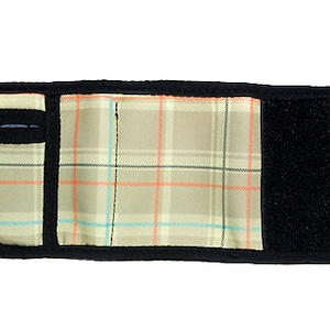 Puede incluir: Una cartera negra con un forro de tela a cuadros y una correa de velcro. La cartera está abierta y el interior es visible.