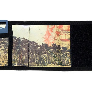 Puede incluir: Un parasol para coche negro con un bolsillo con cremallera y un abridor de botellas. El parasol presenta un gráfico colorido de una escena de la jungla con una boca grande.