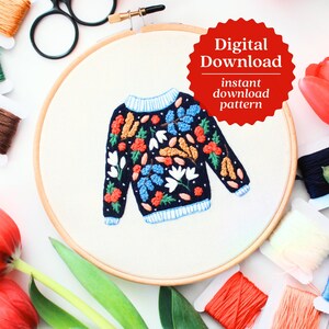May include: Embroidered floral sweater pattern in a hoop. The pattern features a dark blue sweater with colorful flowers, berries, and leaves. The text "Digital Download instant download pattern" is on a red starburst.