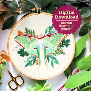 May include: Embroidered hoop art featuring a green luna moth with red and white accents surrounded by green leaves and flowers. The hoop is made of wood and has a white fabric background. The text "Digital Download instant download pattern" is on a pink starburst.