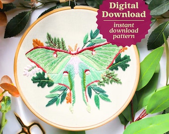 May include: Embroidered hoop art featuring a green luna moth with red and white accents surrounded by green leaves and flowers. The hoop is made of wood and has a white fabric background. The text "Digital Download instant download pattern" is on a pink starburst.