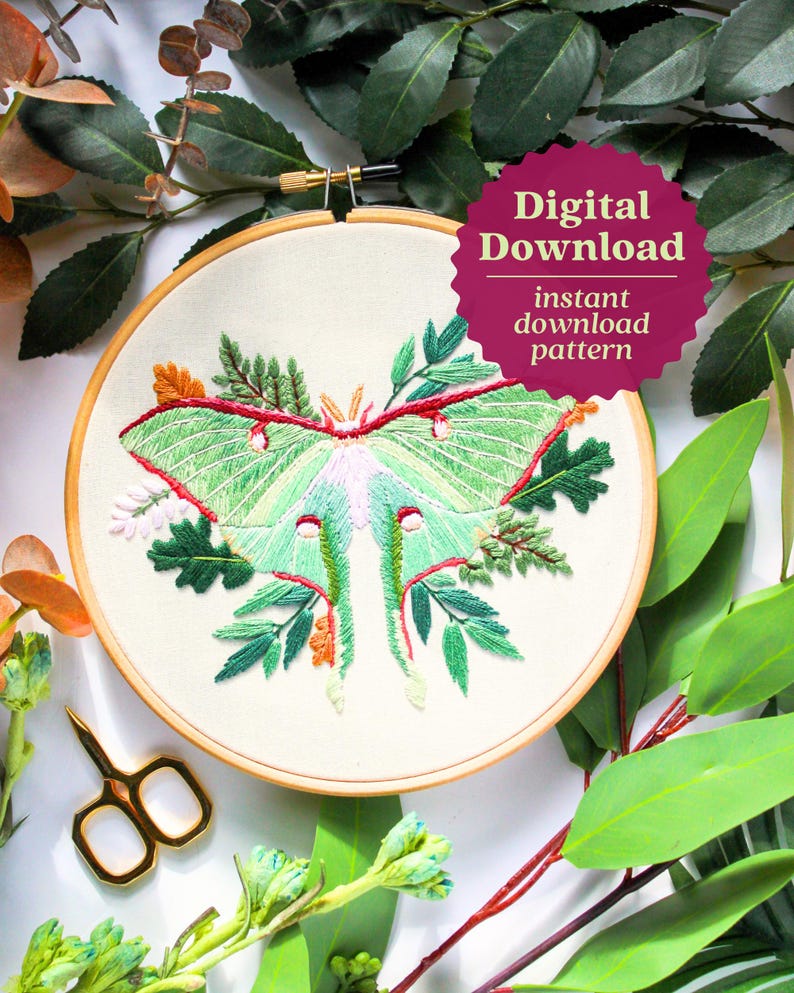 May include: Embroidered hoop art featuring a green luna moth with red and white accents surrounded by green leaves and flowers. The hoop is made of wood and has a white fabric background. The text "Digital Download instant download pattern" is on a pink starburst.