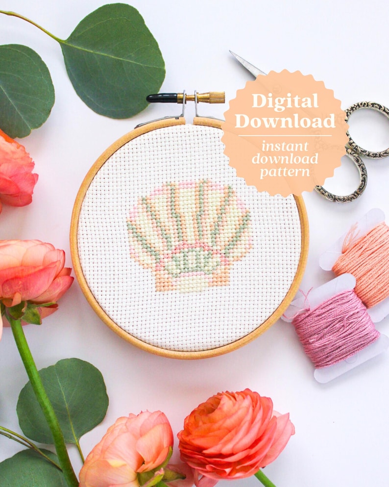 K&ouml;nnte beinhalten: Ein Kreuzstichmuster einer Muschel mit rosa, gelben und gr&uuml;nen Streifen. Das Muster befindet sich in einem h&ouml;lzernen Stickrahmen und ist von rosa Blumen und gr&uuml;nen Bl&auml;ttern umgeben. Der Text "Digitaler Download" und "Sofort-Download-Muster" ist auf dem Bild.