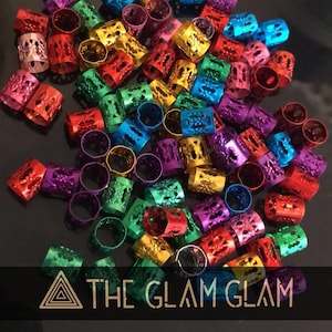 Puede incluir: Un gran surtido de cuentas para el cabello de metal de colores brillantes. Las cuentas son de varios tonos de rojo, verde, azul, morado, dorado y plateado. Las cuentas tienen un diseño decorativo e intrincado.