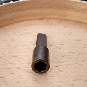 以下が含まれることがあります： 黒酸化仕上げの六角ソケットビットのクローズアップ。ビットは金属製で、わずかに摩耗した外観です。