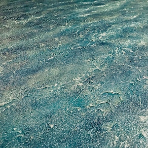 May include: A close-up of a textured blue surface with white accents. The surface has a rough, uneven texture, resembling a weathered or aged material.