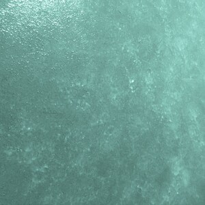May include: A textured, teal green background with a subtle, light, speckled pattern.