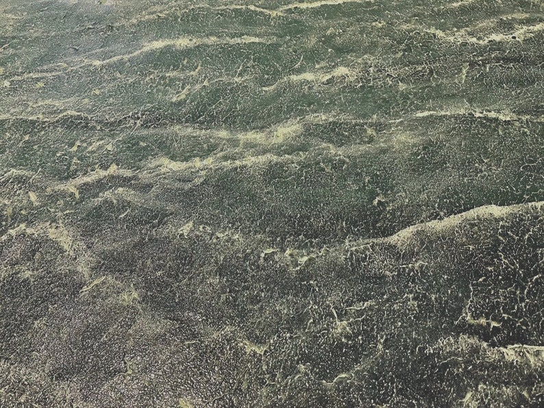 May include: A close-up of a textured surface with a green and yellow color scheme. The surface has a wavy pattern, resembling water.