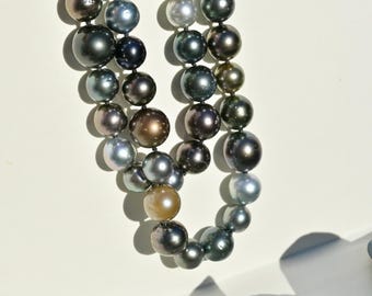 May include: Two strands of lustrous, dark gray and black pearls. The pearls vary in size and have a beautiful iridescent sheen, with hints of silver, bronze, and green. The necklaces are displayed against a white background, showcasing the jewelry.