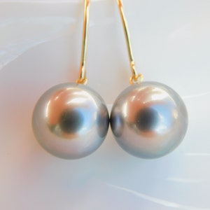 May include: A pair of silver pearl drop earrings with gold hooks.