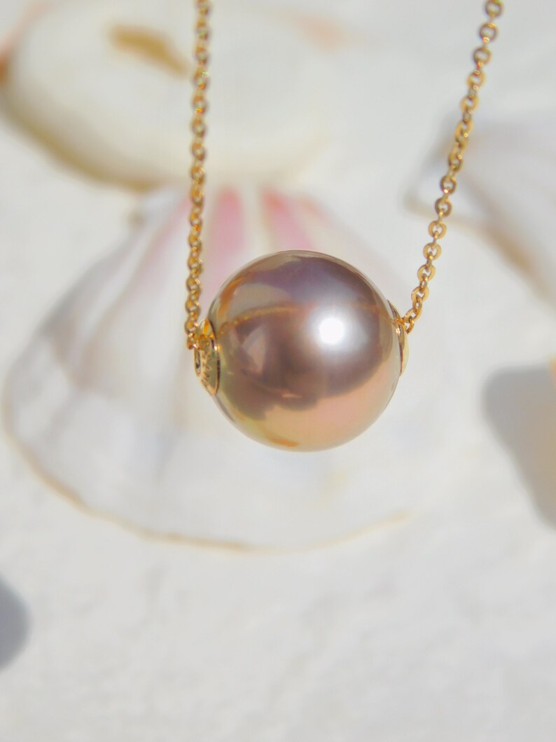 May include: A gold chain necklace with a large, round, iridescent pearl pendant.
