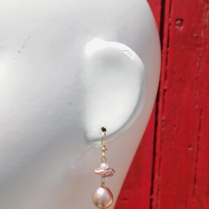 May include: Gold dangle earrings with a pink and white baroque pearl and a smaller white pearl.