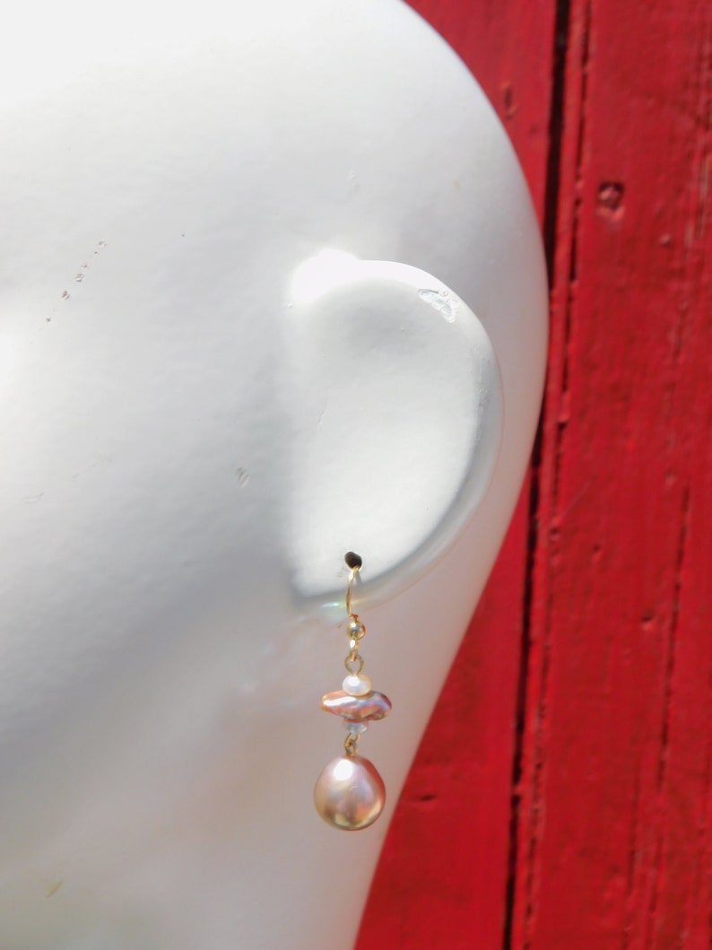May include: Gold dangle earrings with a pink and white baroque pearl and a smaller white pearl.
