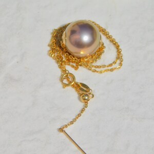 May include: A gold chain necklace with a large, round, iridescent pearl pendant.