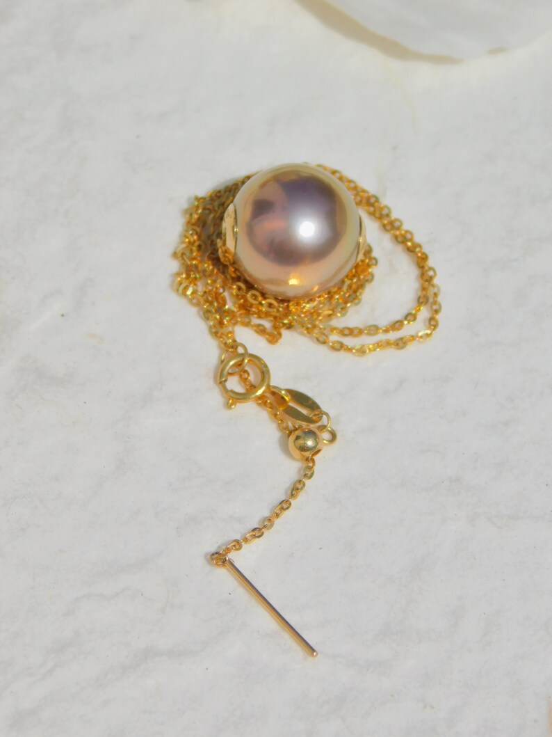 May include: A gold chain necklace with a large, round, iridescent pearl pendant.