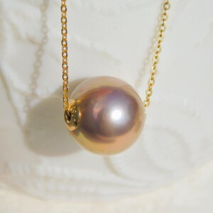 May include: A gold chain necklace with a large, round, iridescent pearl pendant.