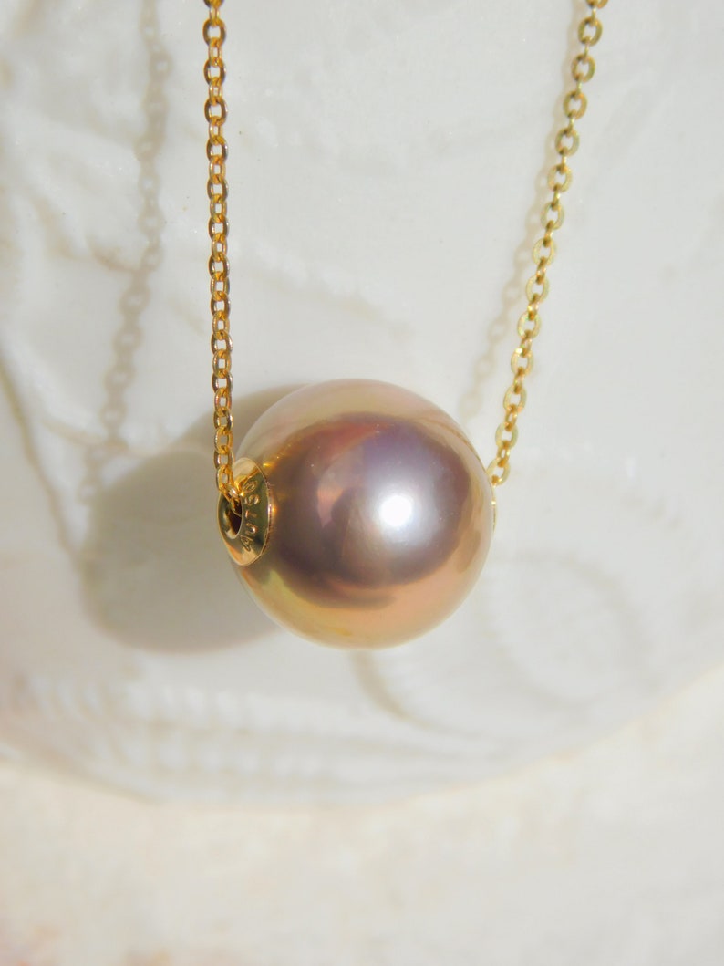 May include: A gold chain necklace with a large, round, iridescent pearl pendant.