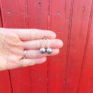 May include: A pair of gold earrings with black pearl drops.