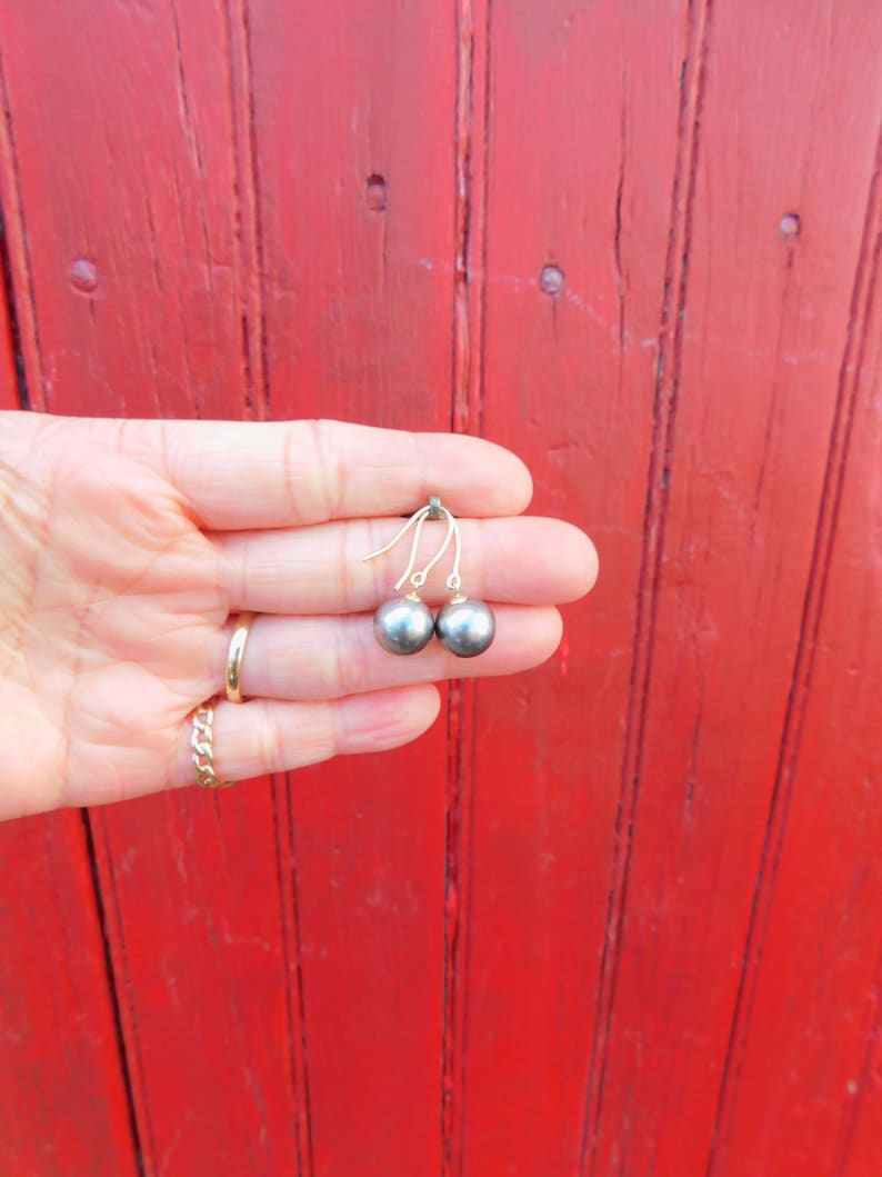 May include: A pair of gold earrings with black pearl drops.