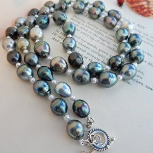 Op de afbeelding: Een dubbele ketting met donkergroene en witte parels. De ketting heeft een zilveren sluiting.