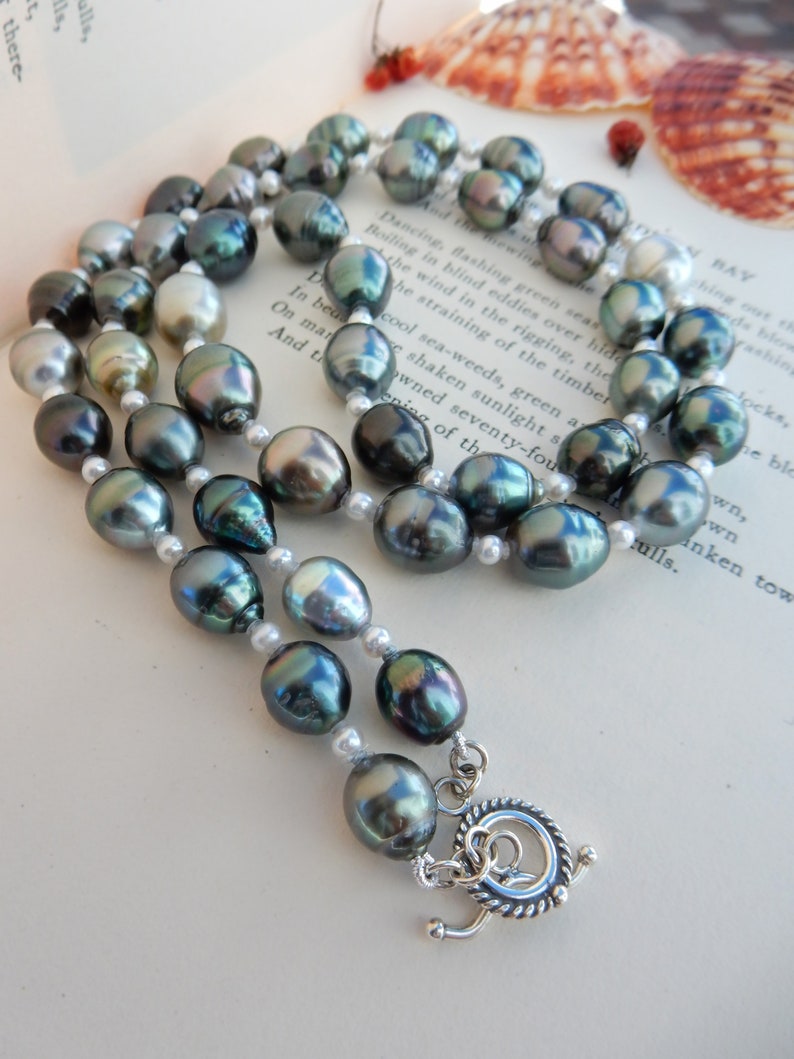 Op de afbeelding: Een dubbele ketting met donkergroene en witte parels. De ketting heeft een zilveren sluiting.