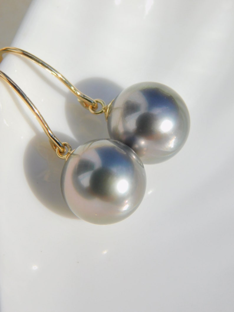 May include: A pair of silver gray pearl earrings with gold hooks.
