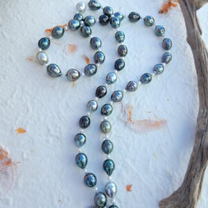 Op de afbeelding: Een ketting gemaakt van zwarte en witte parels. De parels zijn geregen aan een zilveren ketting en hebben een zilveren sluiting.