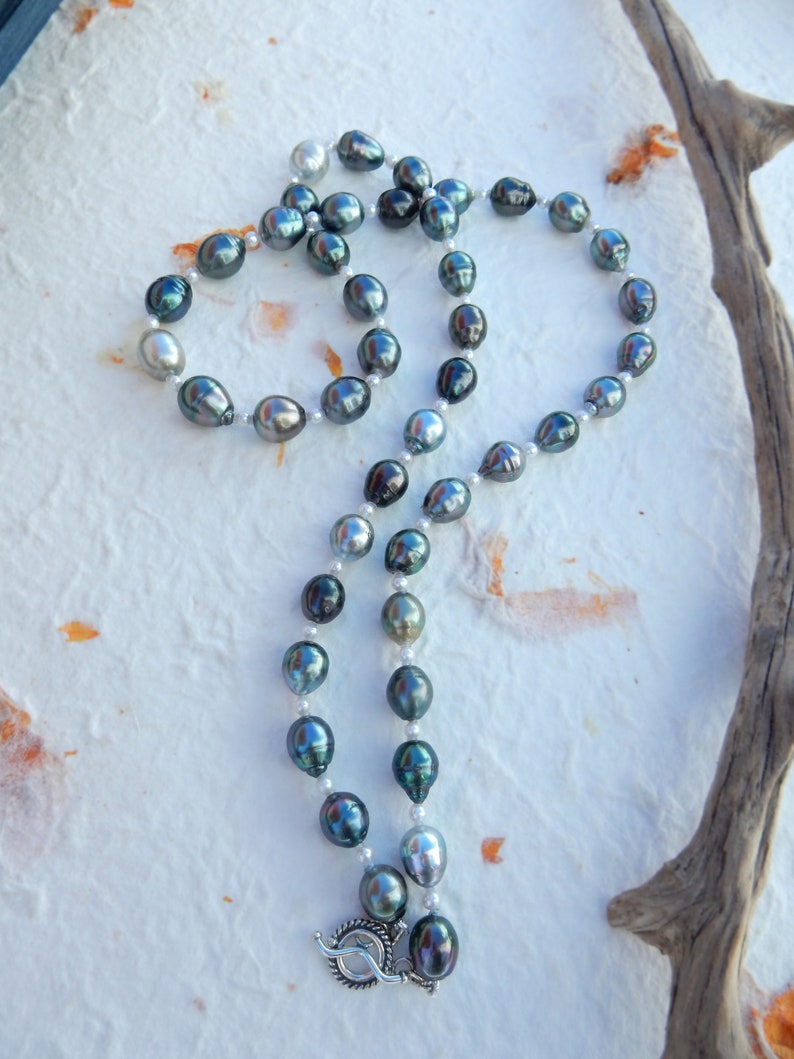Op de afbeelding: Een ketting gemaakt van zwarte en witte parels. De parels zijn geregen aan een zilveren ketting en hebben een zilveren sluiting.