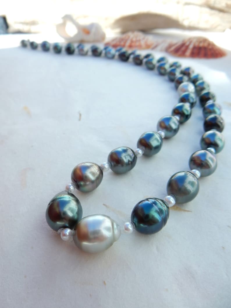 Op de afbeelding: Een ketting van donkergrijze en zilveren parels met zilveren sluitingen. De parels zijn groot en rond.