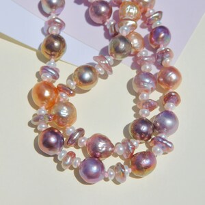 May include: A double strand pearl necklace with pink, white, and peach colored pearls. The pearls are of varying sizes and shapes.