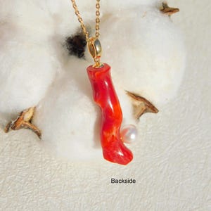 May include: A red coral pendant necklace with a small white pearl accent. The necklace is made of gold chain and the pendant is attached to a gold bail.