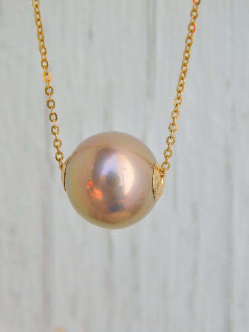 May include: A gold chain necklace with a large, round, iridescent pearl pendant.