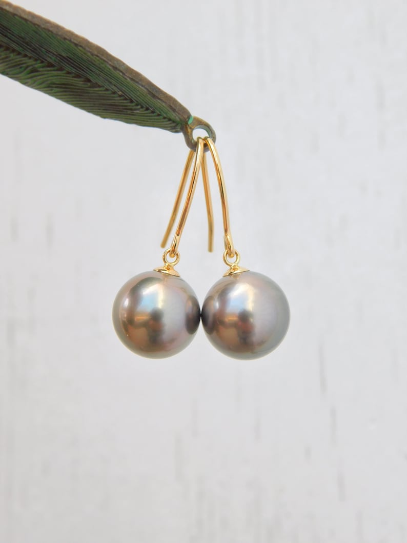 May include: A pair of gold dangle earrings with dark gray pearl drops.