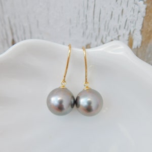 May include: A pair of gray pearl drop earrings with gold hooks. The pearls are round and have a slight iridescent sheen.