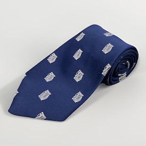 Può includere: Una cravatta blu navy arrotolata con un motivo ripetuto di forme rettangolari bianche scarabocchiate. La cravatta è realizzata in tessuto liscio ed è adatta per abiti formali o da lavoro.