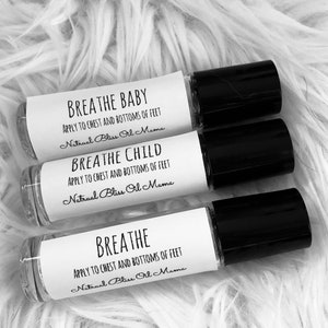 May include: Three white roller bottles with black caps. Each bottle has a label with the text "BREATHE" followed by "BABY", "CHILD", or just "BREATHE". The labels also include the text "APPLY TO CHEST AND BOTTOMS OF FEET" and "Natrual Bliss Oil Mama".