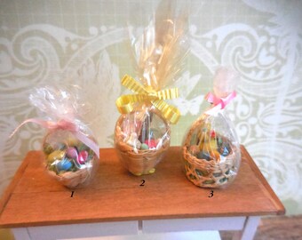 May include: Three miniature wicker baskets filled with colorful Easter eggs, wrapped in cellophane and tied with ribbons. The baskets are arranged on a wooden table.
