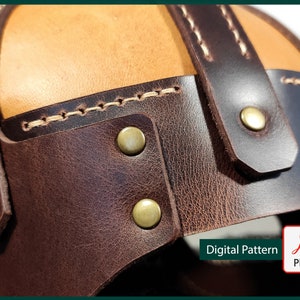 May include: Close-up of a brown leather helmet with a tan leather top. The helmet has decorative stitching and brass rivets.