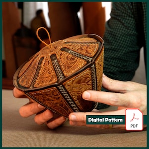 Peut inclure: Une boîte en cuir marron avec des motifs géométriques complexes et un accent doré. La boîte a un couvercle à charnière et une boucle en cuir pour l'ouverture. La boîte est tenue dans les mains d'une personne. Modèle numérique PDF.