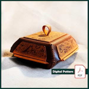 May include: A brown leather box with a decorative paisley pattern and a loop handle. The box has a rectangular shape with angled sides and is stitched together. The text "Digital Pattern" and a PDF icon are visible.
