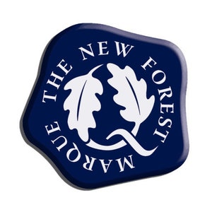 May include: A navy blue emblem with white text and a white oak leaf design. The text reads "THE NEW FOREST MARQUE". The emblem has a rounded, irregular shape with a slight shadow effect.