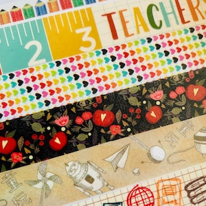 May include: Assortment of colorful washi tapes with various patterns, including pencils, a ruler, hearts, apples, and a robot. The tapes are labeled "2", "3", and "TEACHER".