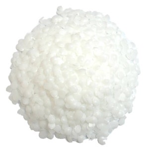 May include: White wax flakes for candle making. The flakes are small and round, and they are piled high in a mound.