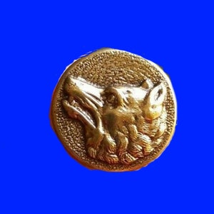 May include: A gold-colored metal button with a detailed wolf head design. The wolf's head is facing to the right and has a textured fur pattern.