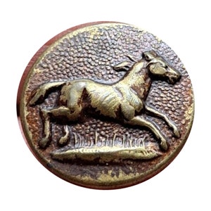 May include: A round, brass button with a raised image of a horse running to the right. The horse is in a relief design and the button has a textured surface.