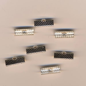 May include: Silver metal clasps for jewelry making. The clasps are rectangular with a small loop on one end. There are seven clasps in the image.