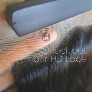 May include: Close-up of a black lace wig with a fine mesh, showing the hair texture and the lace material. The text "Check out our HD Lace" is visible in the image.