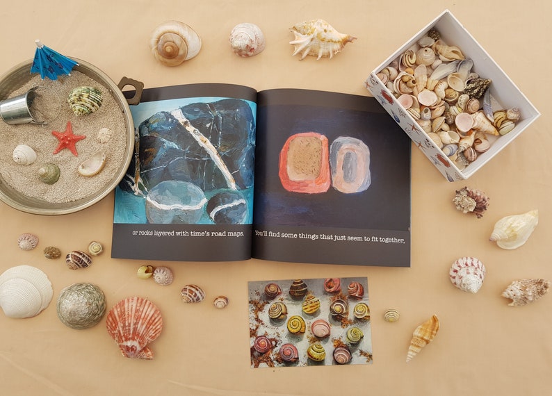 May include: A collection of seashells in various shapes, sizes, and colors, including a small bowl filled with sand and seashells, a box of seashells, and a book with the text "You'll find some things that just seem to fit together."