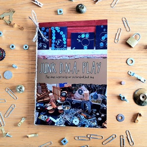 May include: A book titled "Junk D.N.A. Play" with a colourful collage of recycled materials on the cover. The book features play ideas inspired by the picture book "Junk dna".
