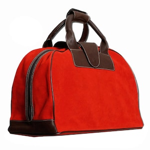 May include: A red suede travel bag with brown leather accents and a top handle. The bag has a zipper closure and a brown leather trim around the bottom.